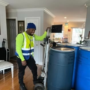 Afford It crew member picking up labeled shipping barrels inside a customer home