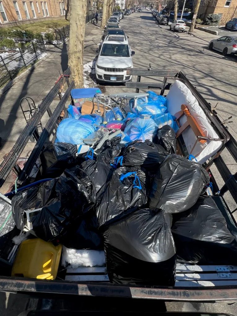 Afford It truck bed loaded with bags, a mattress and household items from a junk removal job